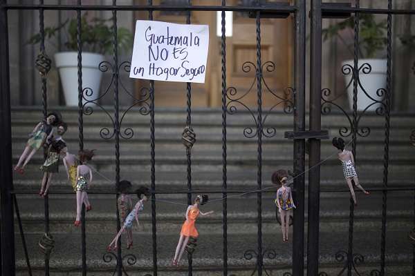 Charred Dolls With a Sign Reading "Guatemala Isn't a Safe Home"